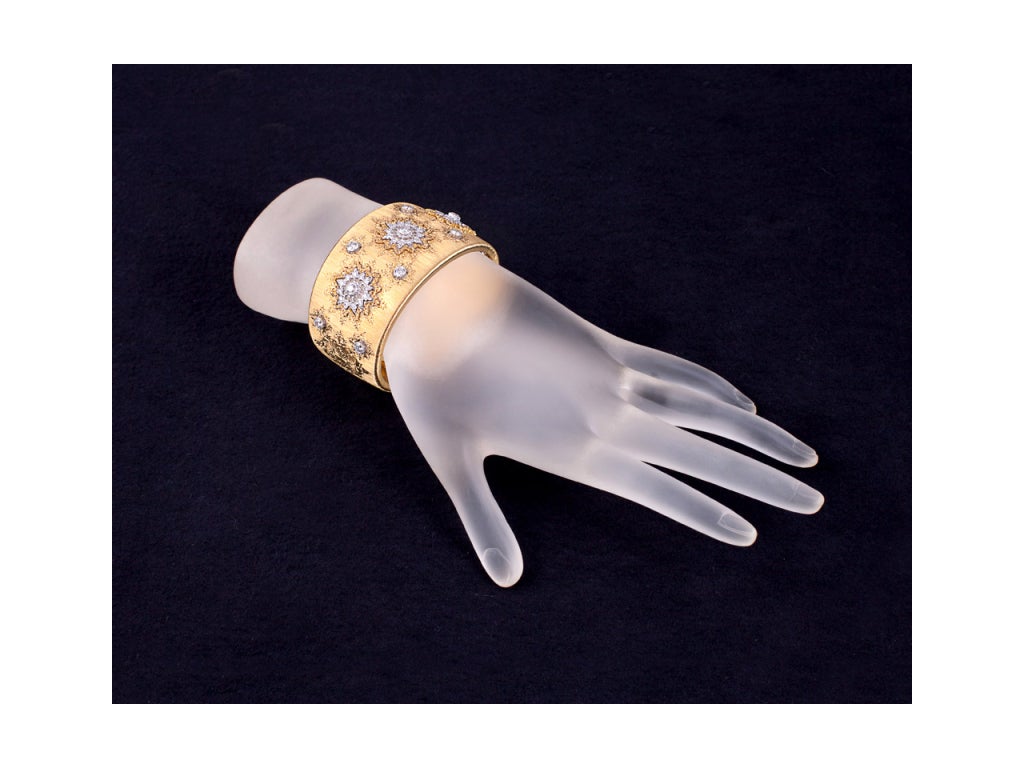 Wide textured gold cuff bracelet centering 3 round diamond-set openwork foliate motifs alternating with bezel-set diamonds in similar motifs. Signed 