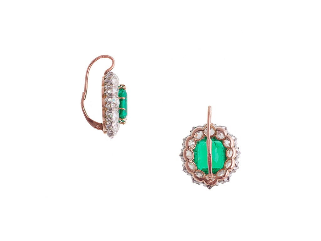 Each earring is backed in 18 karat gold, topped in platinum and centers 1 octagonal step-cut Colombian emerald surrounded by 12 prong/bezel-set old European-cut diamonds and completed by a 14 karat gold wire and lever back. The emeralds weigh 3.78