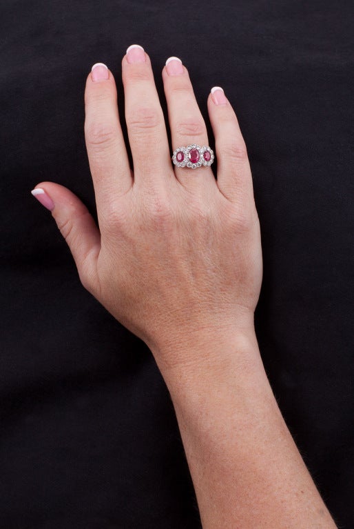 The ring is composed of 18 karat gold, the top rhodium-plated, and set with 3 oval rubies and 26 round diamonds, with English hallmarks. Total ruby weight is approximately 2.89 carats, total diamond weight is approximately 1.05 carats, color: G-H,