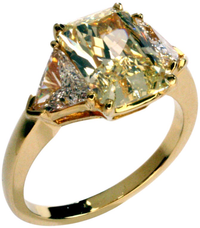 Traditional fancy yellow canary diamond Cartier ring with white diamond trillions.  Center rectangular cut-cornered diamond is 3.06 carats with color rated natural fancy yellow.  Clarity is VS2.  Setting is 18 karat gold.  Signed Cartier with