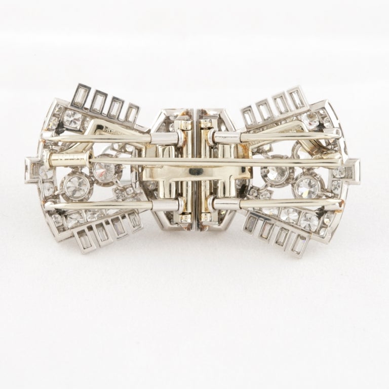 A French Art Deco platinum and diamond clip/brooch by Mauboussin. The brooch separates from its frame into two dress clips that feature round and baguette-cut diamonds with an approximate total weight of 8.50 carats. With the original signed and