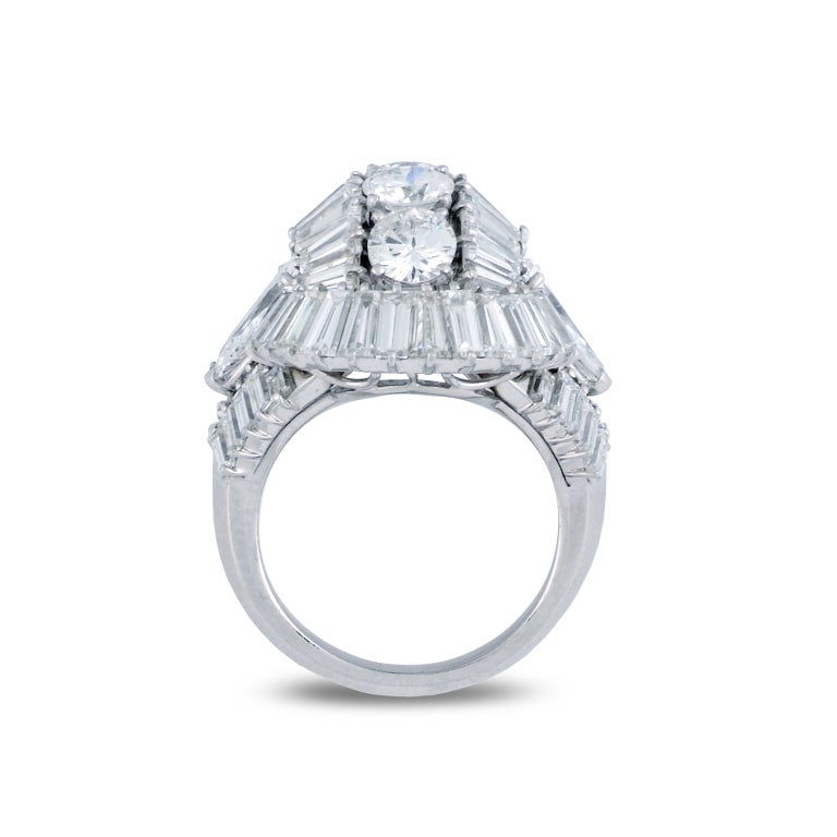 Designed as a domed centre set with radiating baguette-cut diamonds, centring on a line of brilliant-cut diamonds, accented to either side by a pear-shaped diamond, within a surround of baguette stones, circa 1950, French assay marks for platinum,