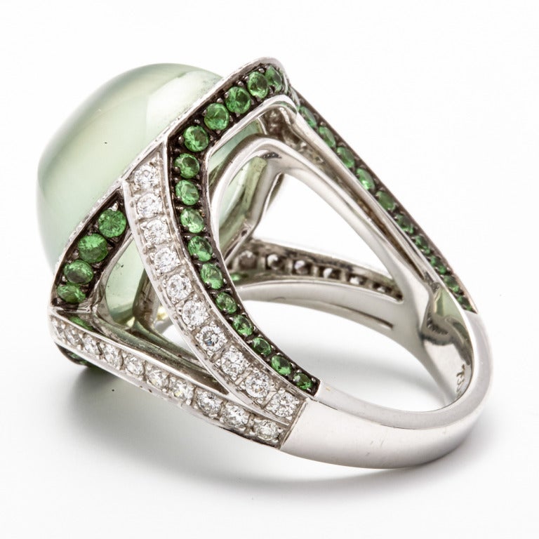 A modern 18K white golden, tsavorite, diamond and prehnite dress ring, the central stone is a prehrite square cabochon cut and is surrounded by brilliant cut diamonds. The gallery of the ring is set with over 60 round cut tsavorite stones and