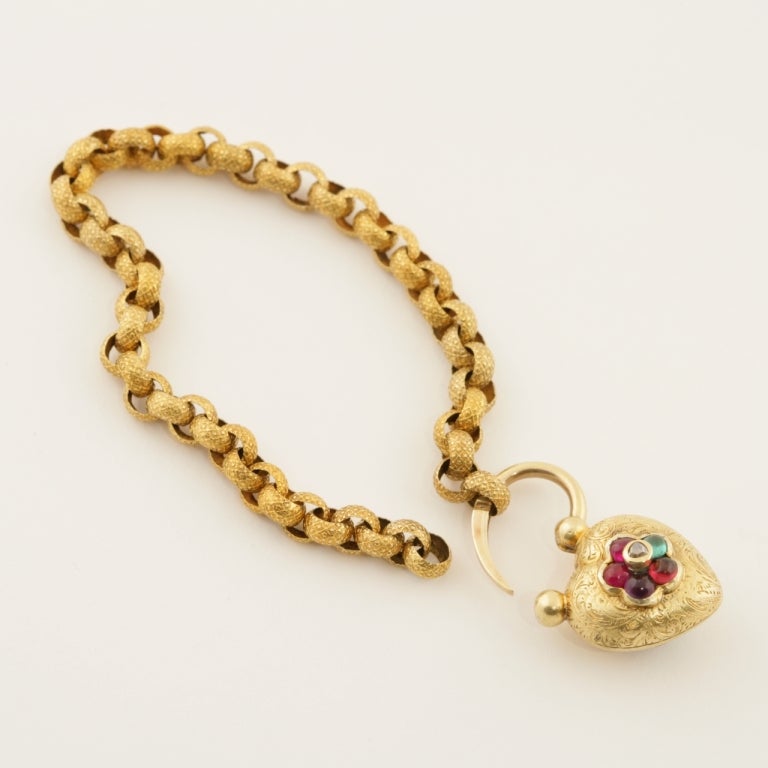 An English Antique bracelet with diamond, rubies, emerald, garnet and amethyst. The 15 karat bracelet has 1 rose-cut diamond, 2 cabochon rubies, 1 cabochon emerald, 1 cabochon garnet and 1 cabochon amethyst in a heart shaped 18 karat gold locket