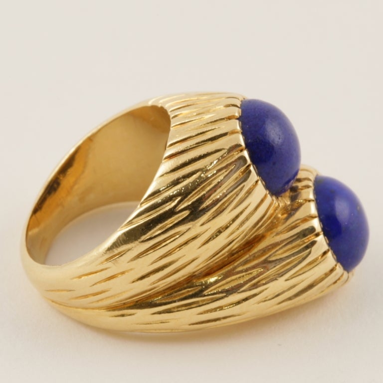 A French Mid 20th Century 18 karat gold ring with lapis lazuli by Cartier Paris. The ring has 2 cabochon Lapis Lazuli stones set in a high double ring deeply carved ring.
(MG Inventory #R15764)

Circa 1970’s. 

Signed, Cartier Paris French