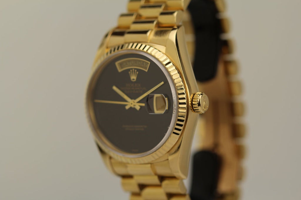 This is a Rolex 18k yellow gold Day-Date President wristwatch, Ref. 18038, with an Onyx dial. It has a fluted bezel and is on a yellow gold Rolex President bracelet.