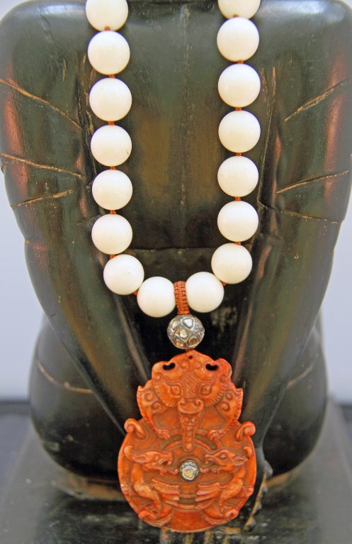 Large hand-carved jade figure of 3 dragons encrusted with a diamond belly button and a diamond bead crown, intricately macraméd to white coral beads.

1.30 TCW uncut diamonds
Overall length:  19
