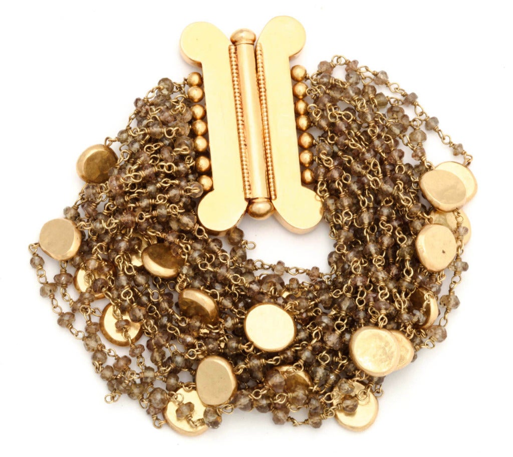 A bracelet composed of 21 strands of garnets which have been pigtailed with 18kt yellow gold wire and have 18kt yellow gold disc beads scattered among the rows of faceted garnets. There is an 18kt yellow gold clasp which measures 1.75 inches in