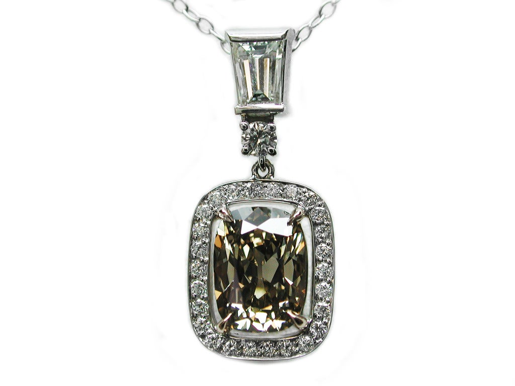 This 2.03ct fancy orangey brown cushion cut diamond is set in pink gold and surrounded by 0.32ctw of white round brilliant diamonds set in white gold. This pendant dangles from a 0.34ct baguette.