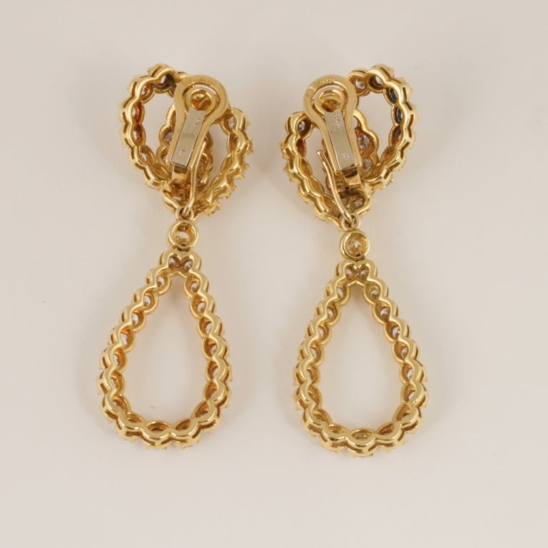 A pair of French Estate 18 karat gold ear pendants with diamonds by Verger. The earrings have 83 round-cut diamonds with an approximate total weight of 14.00 carats. The earrings are composed of a double entwined pear-shaped diamond formed top from