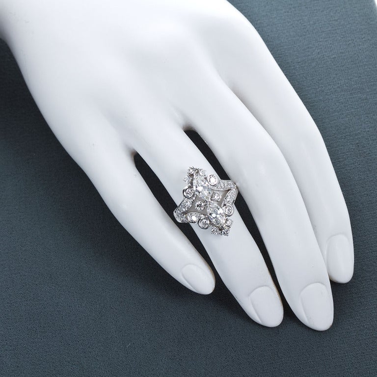 A 1940s ring with near colorless and VS1+ quality diamonds of ~4.40 carats total weight. This ring is as fine and inspiring as can be. In high quality round and marquise shaped diamonds (~0.80 ct each) set end to end with ornate retro scroll style