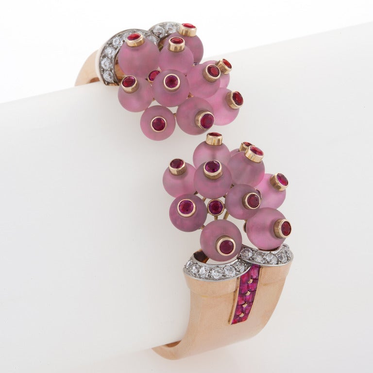 Composé d'or rose chaud, cet audacieux bracelet manchette Georges Verger, avec ses perles de quartz rose givré, de rubis et ses arcs de diamants entrecroisés, se glisse sur le poignet pour un port glamour du jour au soir. Les frères Georges et Henri