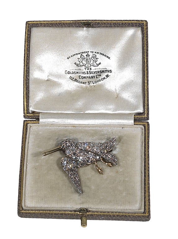 
Modelled as a snipe in flight, mounted in gold and silver and set throughout with old-cut and rose-cut diamonds, with ruby cabochon eye, in fitted Goldsmiths & Silversmiths Co Ltd box, length 3.5cm.
Weight: 5.4g