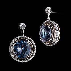 Brilliant-cut vivid London Blue Topaz is suspended by a pair of Brilliant-cut Diamonds surrounded by Alexandra Mor's signature floating Diamond melee and 1mm knife-edged wire. Earrings are set in platinum on 18 karat yellow gold Alexandra Mor logo