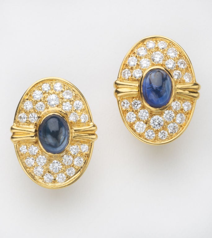 A stunning pair of 18 karat gold earrings with diamonds and sapphires by legendary jeweler, Harry Winston.  The 1.5 carat  cabochon sapphire is surrounded by 26 full cut diamonds for an approximate total of .78 carats in each earring.  The diamonds