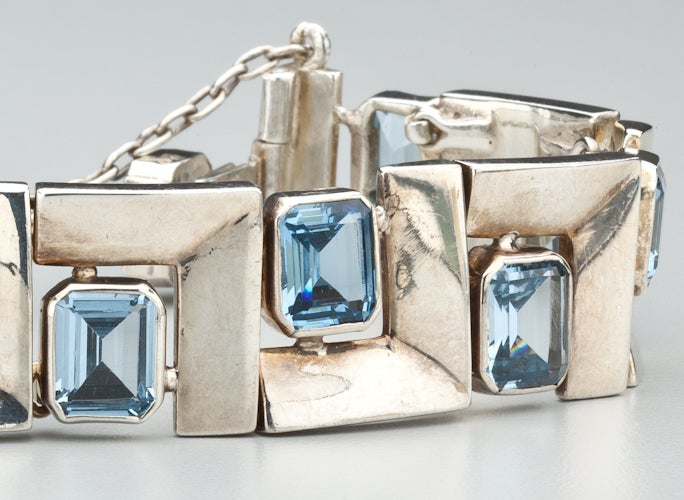 A geometric link bracelet by Mexican modernist designer, Antonio Pinda (1919-2009),  The bracelet is made of sterling silver links highlighted by ten square cut blue topaz.  Even the clasp is accented with blue topaz.  The bracelet is hallmarked
