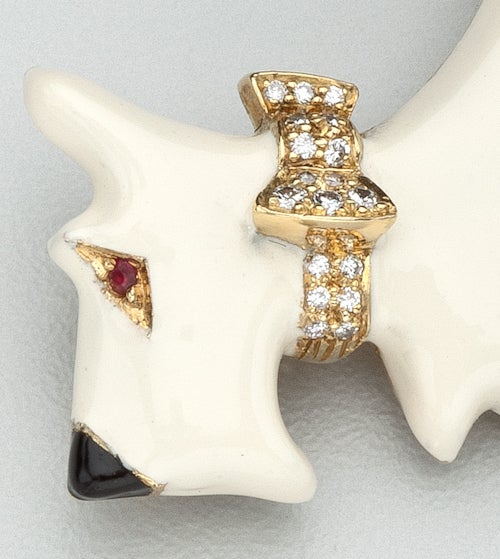 An 18 karat gold and enamel brooch of a terrier.  He has a white enamel body, a black enamel nose, a ruby eye and 18 pave set diamonds in the collar.  The diamonds  weigh approximately .50 carats.   The brooch is signed on the back with English