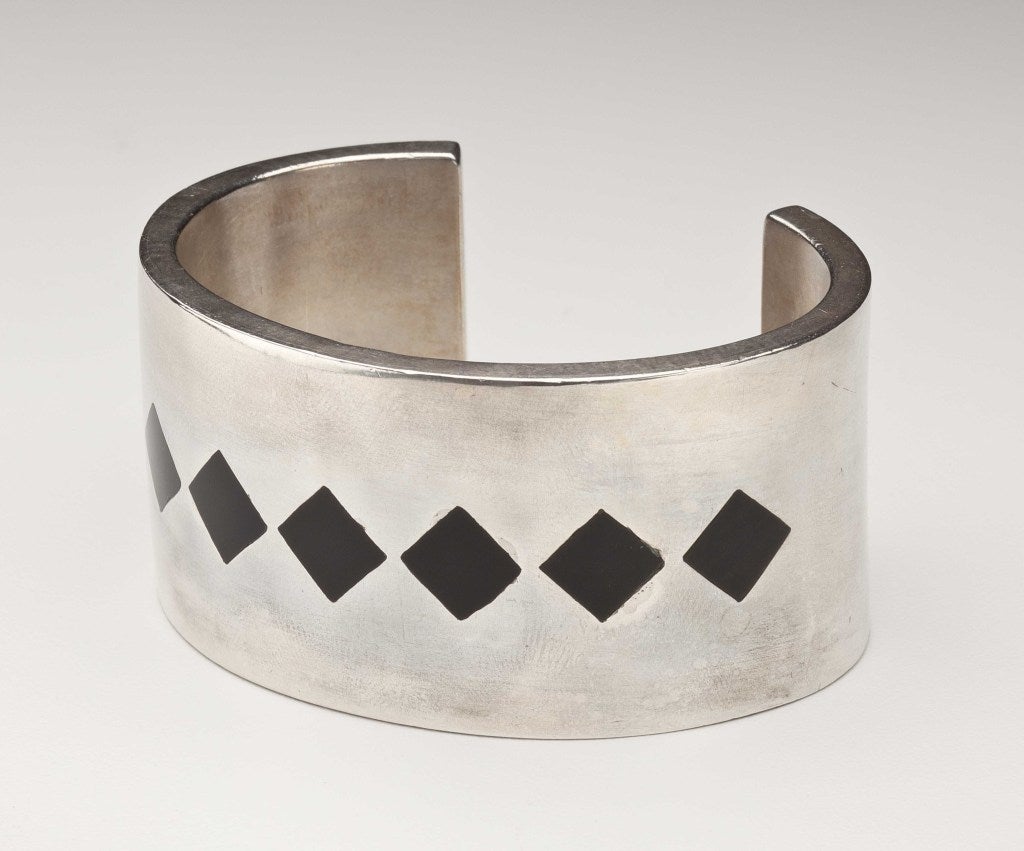 A cuff bracelet by the Mexican silver designer Antonio Pineda (1919-2009), in sterling silver with inlaid diamond shaped obsidian.  It is hallmarked with the Antonio crown, used from 1953 to the present day, along with the eagle 17 and the inventory