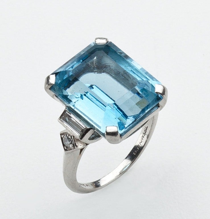 An aquamarine and diamond ring set in platinum by Tiffany.  Prong set with an emerald cut aqua measuring 15 x 12.3 x 7.7 mm flanked by baguette and old European cut diamonds. Signed Tiffany & Co., irid.  Size 5 1/2.