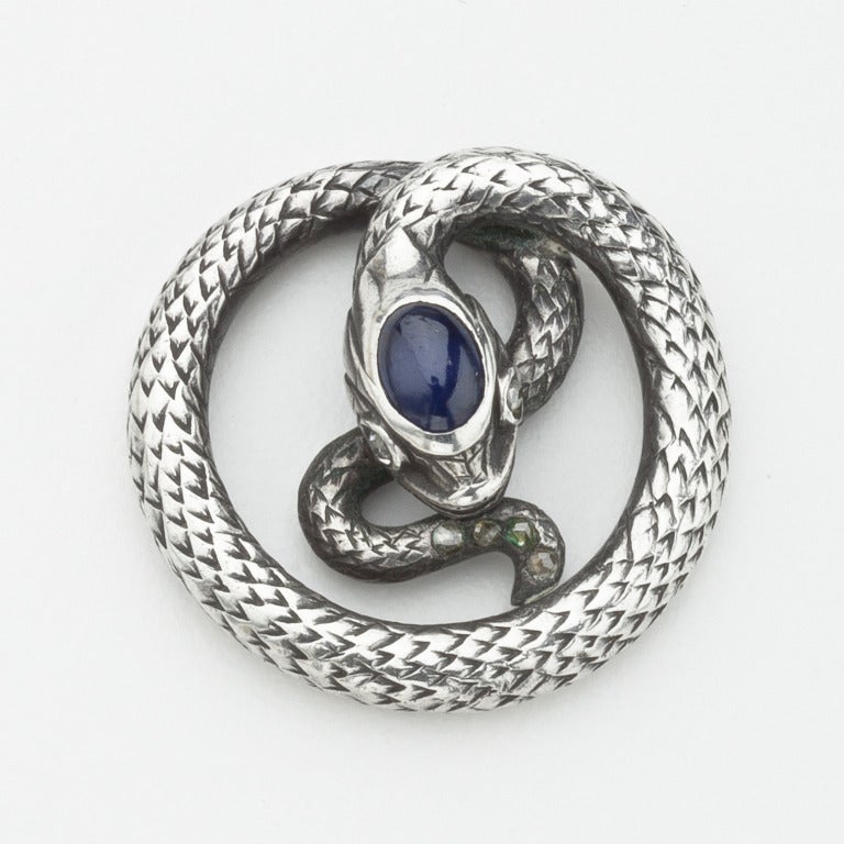 A pendant of a rattlesnake with Czarist Russian hallmarks.  The coiled sterling silver snake, which is exquisitely textured to resemble scales,  has a sapphire in his head and rosecut diamond melee in his eyes and tail.   The pendant is hallmarked