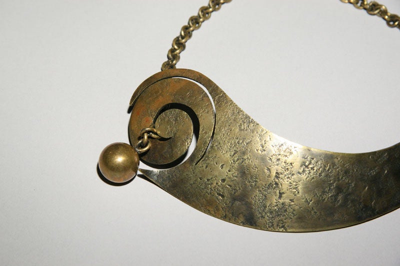 An abstract modernist necklace by renowned Greenwich Village jeweler, Art Smith (born Cuba 1917-died New York City 1982).  The textured form shows Smith's hand hammering and includes a moveable ball on a chain that serves as the closure.  Smith