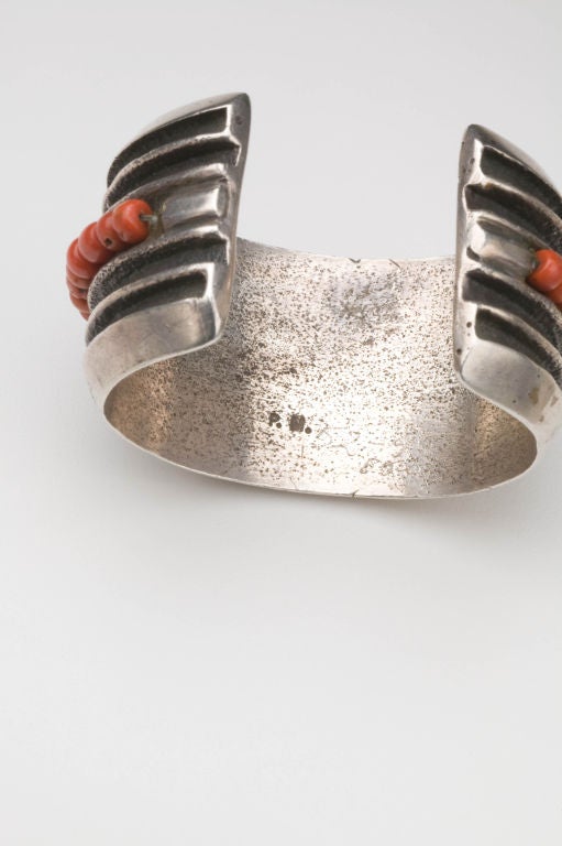 A tufa cast sterling silver cuff bracelet with coral accents by Native American master silversmith, Preston Monongye (1927-91).  Hallmarked on the interior with PM mark.  This bracelet is a heavy cast silver fitting firmly on the wrist.