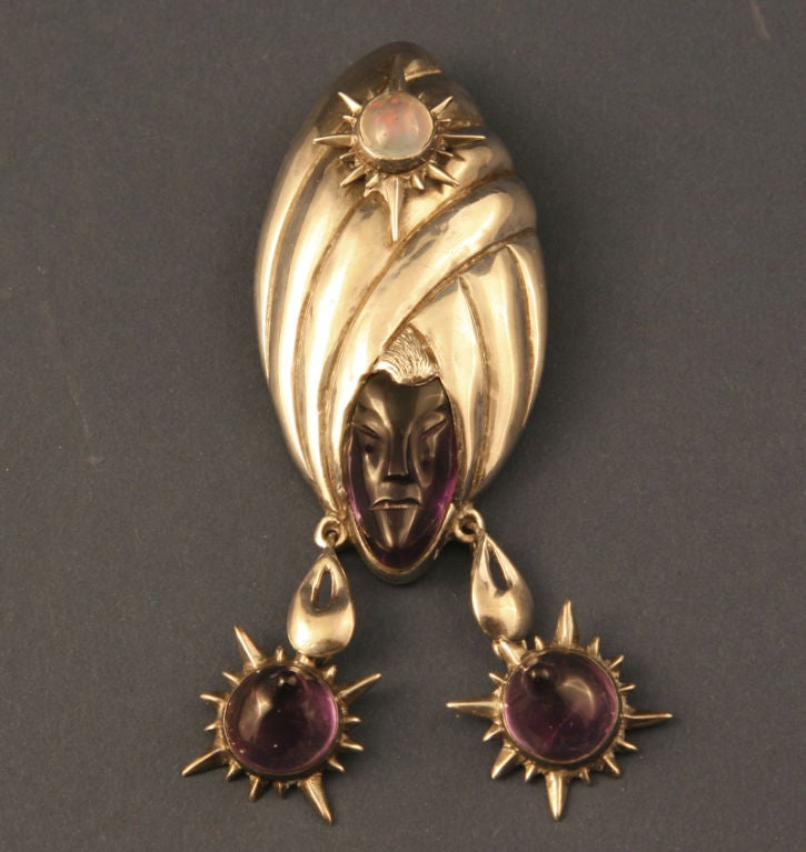 A rare brooch and earrings set by Antonio Pineda designed as an exotic turbaned head of a woman.  The head is carved from amethyst; her breasts are amethysts and an opal is set in her turban.  The hallmark 