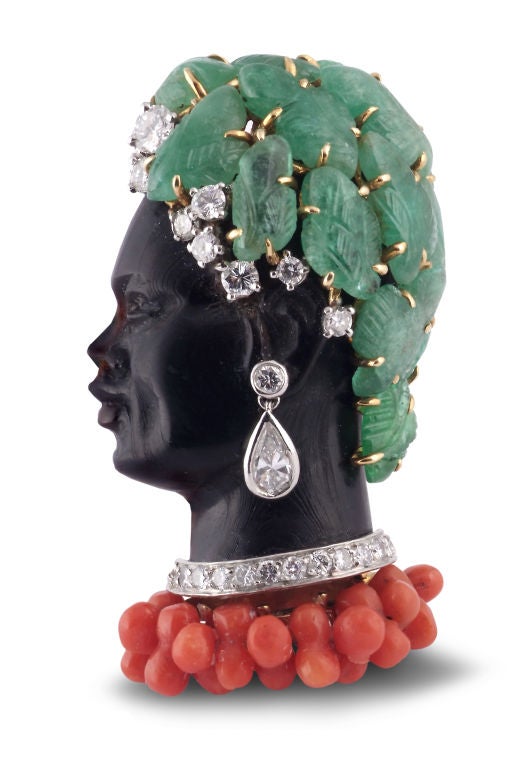 Designed as a carved onyx female bust, the hairline embellished with carved emeralds accented with brilliant-cut diamonds, the ear suspending a pendent pear-shaped diamond earring, the neckline set with a line of brilliant-cut stones suspending