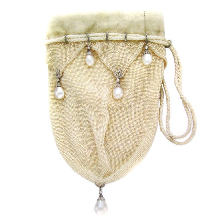 Designed as a seed pearl and white leather pouch, trimmed by seed pearl triangular overlay, suspending pearl drops with circular and rose-cut diamond caps and ribbon detail, to the twin-rope cinch cord, gathered by rose-cut diamond rondelles,