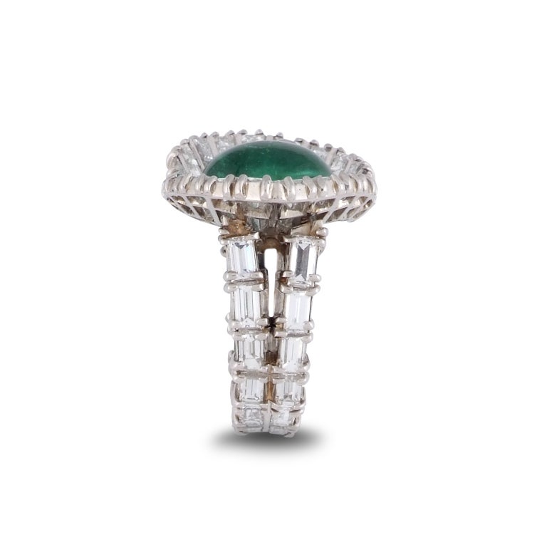 Designed as a central cabochon emerald measuring approximately 12.8 x 10.4mm, between angled pannels set with baguette-cut diamonds, to a similarly-set bifurcated shank, 1950s, signed Sterlé and numbered 8013, French assay marks for platinum, size 4