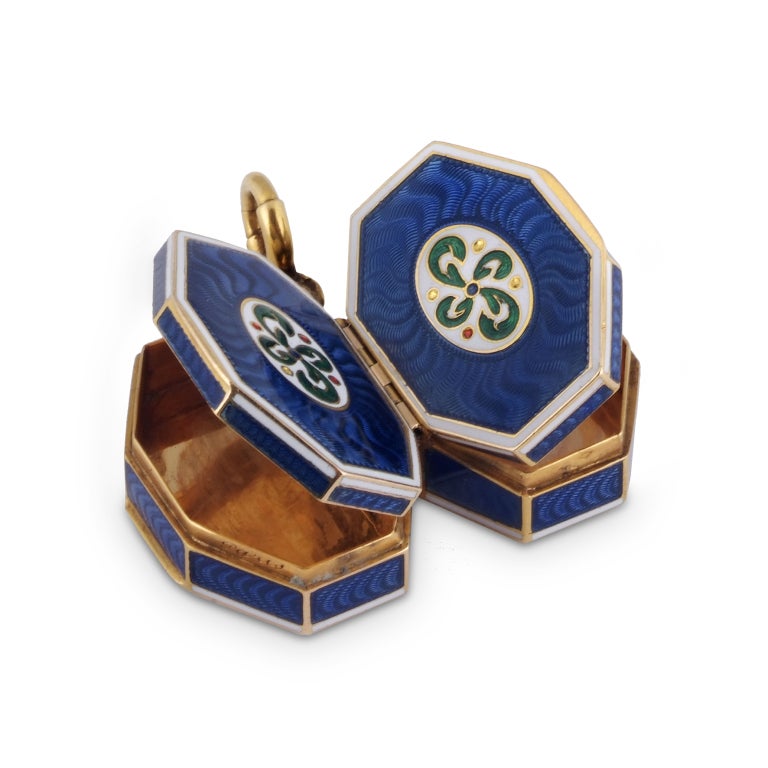 Composed of two octagonal compartments, each applied with blue guilloché enamel to all sides over a radiating motif, within contours of white enamel, the front centring on an oval white enamel section embellished with a scrolling green motif, each