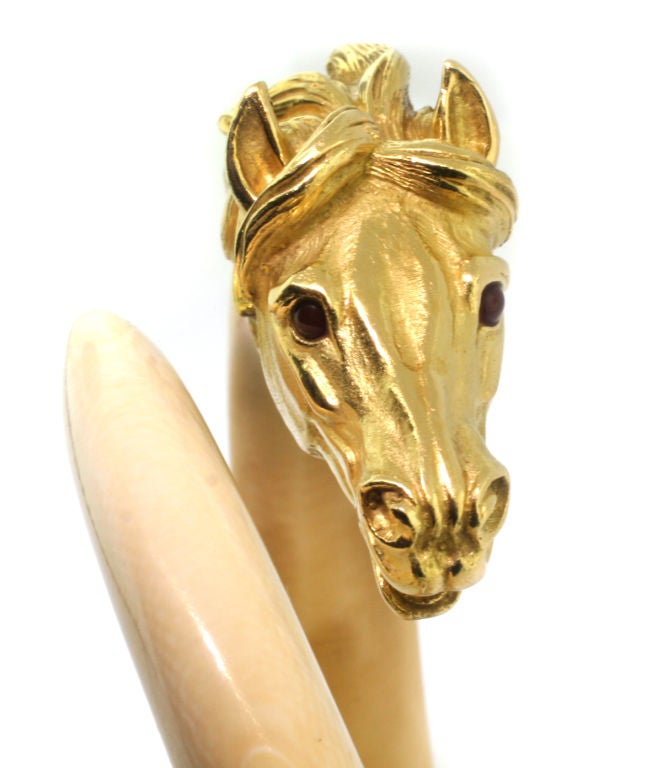 The tapering ivory bangle culminating with a detailed yellow gold horse's head, accented with cabochon agate eyes, circa 1965, Signed VC & A and numbered, French assay marks for 18ct gold.