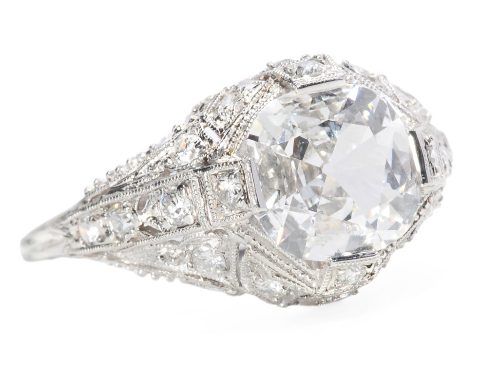 Perfection personified is this superb Edwardian platinum ring set with a round cushion cut diamond (with slightly squared edges) of an actual 1.53 carats, F color and VS1 clarity. The main diamond is not only marvelous but is unusual with a facet