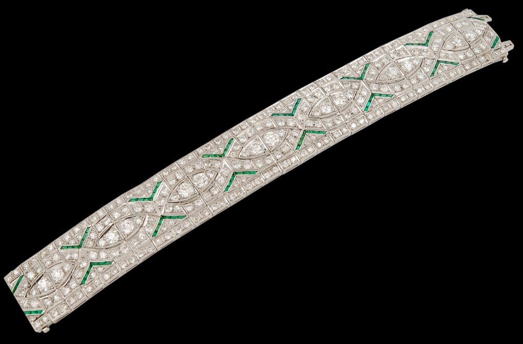 A 1930's Art Deco diamond and emerald bracelet of geometric design; set predominantly with brilliant-cut diamonds and accented with inverted emerald chevron motifs.

Mounted in platinum and set with approximately 20 carats of diamonds.