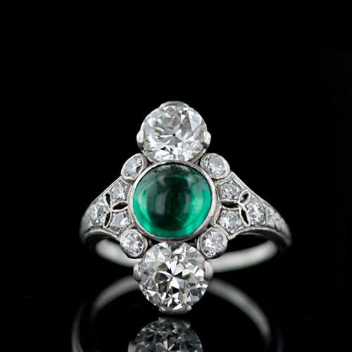 A gorgeous and superb Art Deco gemstone ring by the esteemed New York and Chicago jewelers Dreicer & Co. This 1920's treasure centers on a bright translucent green cabochon emerald which is vertically flanked on each side by two bright white old