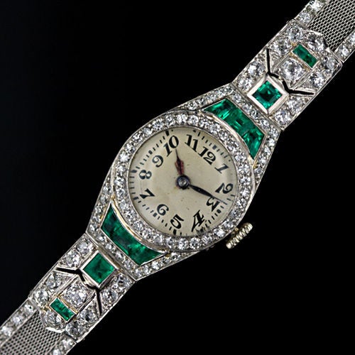 A spectacular high Art Deco bracelet watch circa 1925. Scintillating round diamonds enhanced with good size bright green calibre emeralds are artfully arrayed around the face and on the fine platinum mesh band of this dramatic and sophisticated