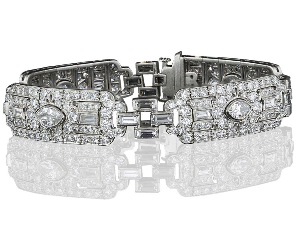 This simply stunning and sparkling original Art Deco bracelet from the mid-1920's is composed of four repeating diamond set sections designed around a central old cut marquise diamond and include two baguette and numerous round diamonds. The elegant