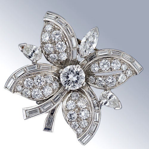 This stunning, diamond packed pin from the mid-20th century is a delight to behold. The central round brilliant cut diamond bursts forth with sparkling diamond petals outlined with diamond baguettes which also serve as the stem. The piece is further