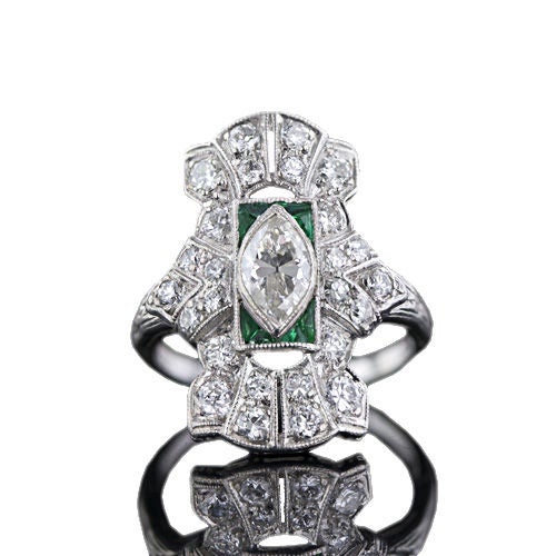 Or a 'dinner' ring (following the cocktails). A half carat marquise-cut diamond, bezel-set in the center and tipped by calibre-cut emeralds and green glass, forms the heart of this unique sparkler. Twenty-six European-cut diamonds flash and shimmer
