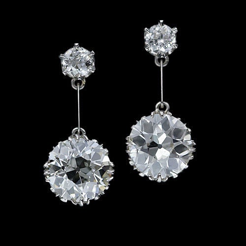 An impressive pair of old European cut diamonds, with the respective weights of 2.75 and 2.50 carats, swing freely on knife edge platinum bars from a matching pair of small old cut diamonds weighing .55 ct. total. The delicate and graceful platinum