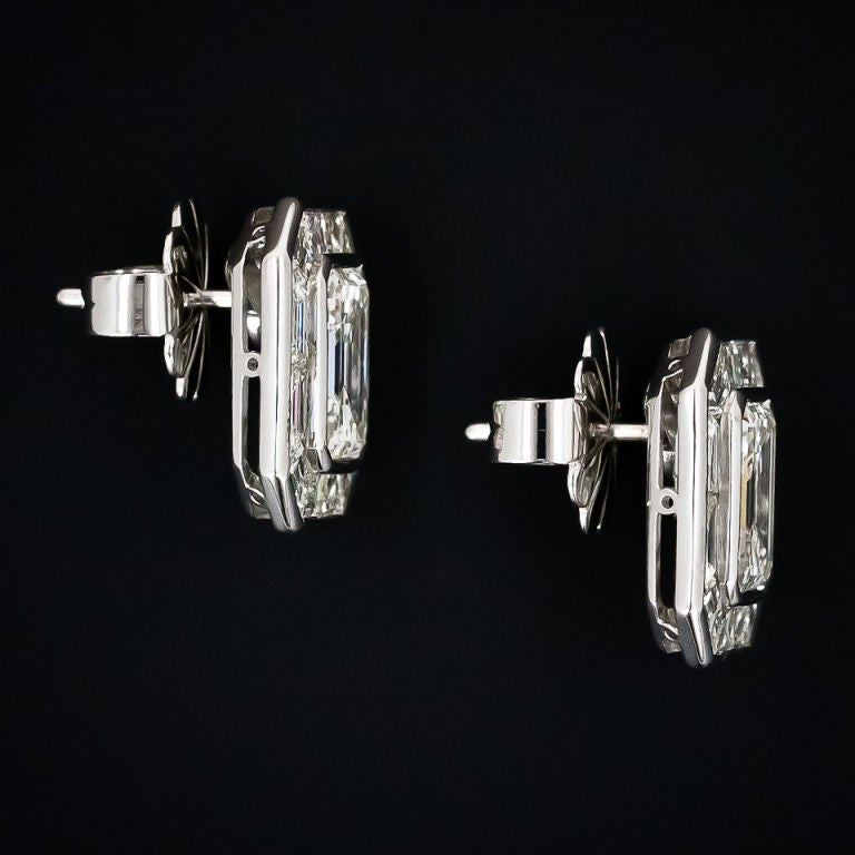 Two substantially sized emerald cut diamonds, 2.77 and 2.76 carats, dazzle in these gorgeous platinum and baguette diamond earrings. The emerald cut diamonds are framed with an outline of over 4.00 carats of precision cut calibrated baguette