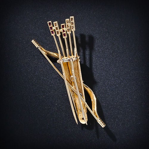 Awaiting Cupid's return is an 18 karat yellow gold bow with a ruby grip embracing a quiver of diamond and ruby arrows. French hallmarks, signed Cartier. 

Inventory No. 50-1-2788