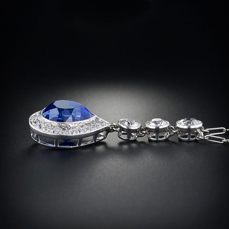 The most stunning, electric blue 6.00 carat natural - no heat Burmese Sapphire, accompanied by an AGL certificate stating as such, dances from this gorgeous Art Deco platinum and diamond pendant from the early 20th century. The sapphire is wrapped
