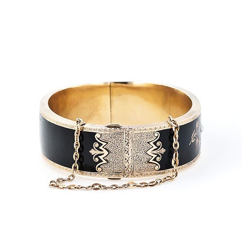 This Victorian classic which was intended long ago as mourning jewelry, in today's day and age makes for a dramatic fashion statement. The hinged gold bangle is colored with glorious black enamel decorated with five shimmering white seed pearls,