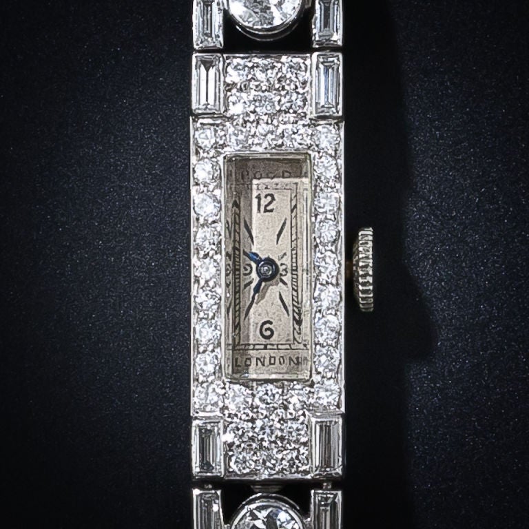 This dreamy dazzling Art Deco diamond bracelet watch centers on a diamond framed rectangular dial with Arabic numerals at 12 and 6, with stick chapters - signed Rood, London. The gorgeous bracelet is composed of a double line of shimmering