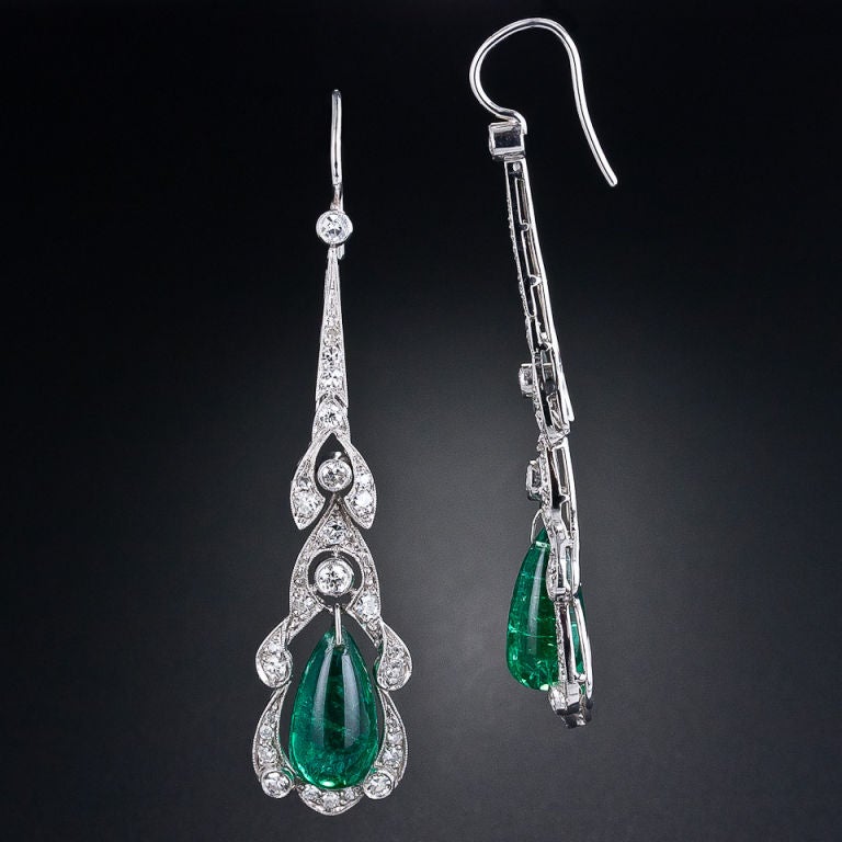 These 2 1/4 inch long and lovely vintage earrings, crafted in platinum in the early 1900s feature a dreamy pair of lively green cabochon tear drop emeralds weighing 8.00 carats. The emeralds swing back and forth inside elegant diamond frames with