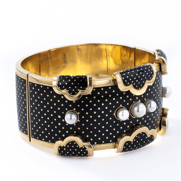 From late-nineteenth century France comes this magnifique 1 and 1/4 inch-wide enameled bangle bracelet topped with five bright white-rose pearls. A wonderful and whimsical tiny polka-dot pattern rendered in dramatic black enamel over rich 18K yellow