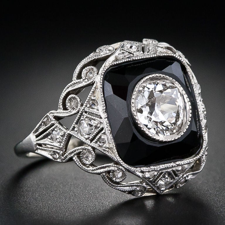 This distinctive antique diamond ring hails from the early-Art Deco period: the late teens-early 1920s. The central bezel-set old mine-cut diamond weighs .70 carat and is effectively highlighted by a faceted black onyx surround, which is also set in