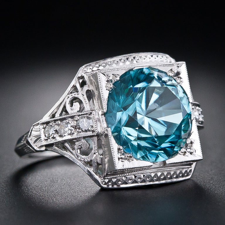 This late Art Deco gemstone ring in glorious blue and white consummately presents a radiant natural blue zircon, weighing 6 carats, in a truly superb, hand-fabricated platinum mounting imbued with a subtle combination of both curvilinear and