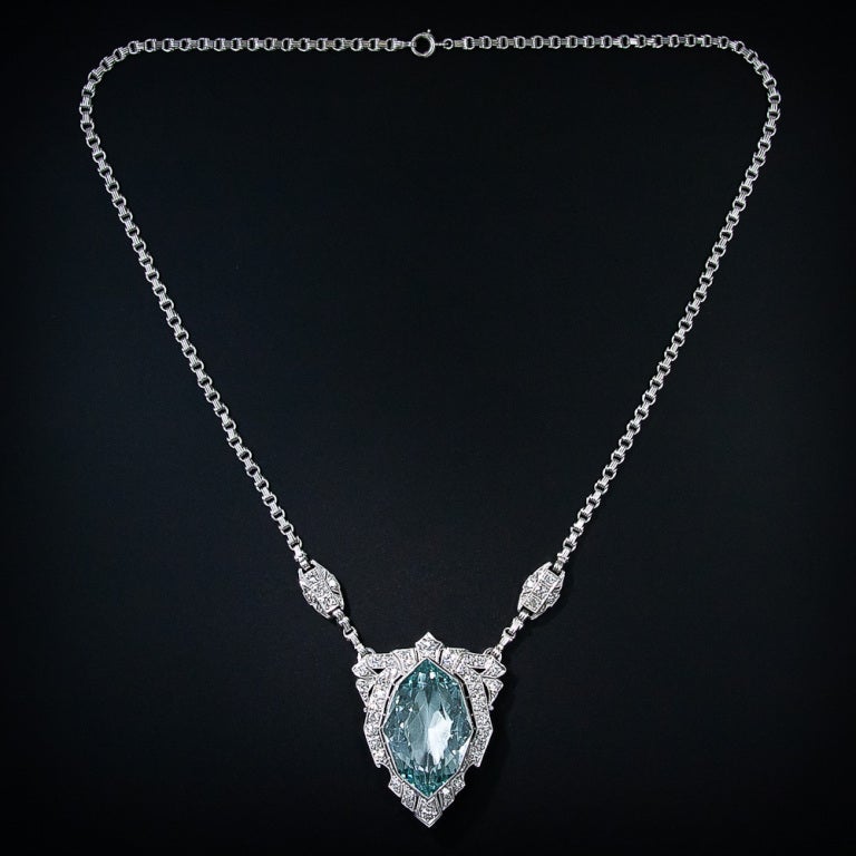 This singular and magnificent original Art Deco necklace, handcrafted in platinum, glistens front and center with an entrancing 28 carat, geometrically stylized, navette-shape aquamarine. The aqua, which displays a cool and soothing pastel blue